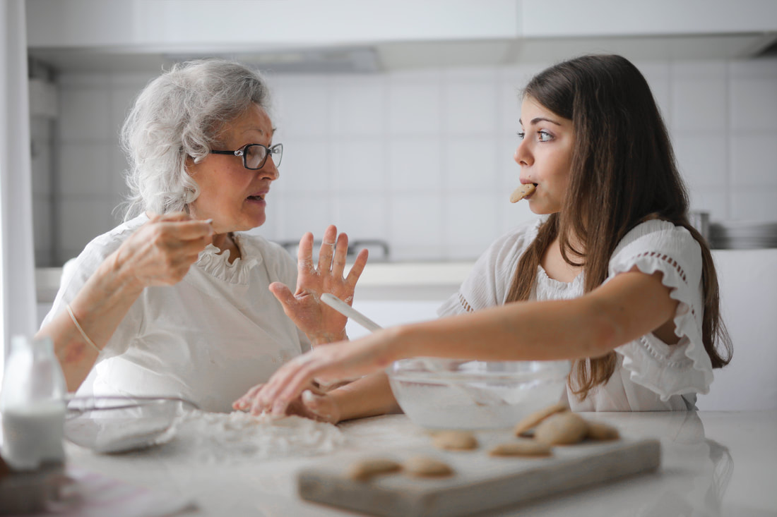 Young girl assisting old woman with baking needs
