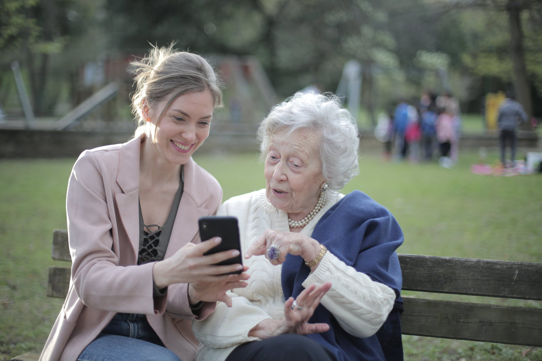 Home health care expert assisting old woman with a smartphone
