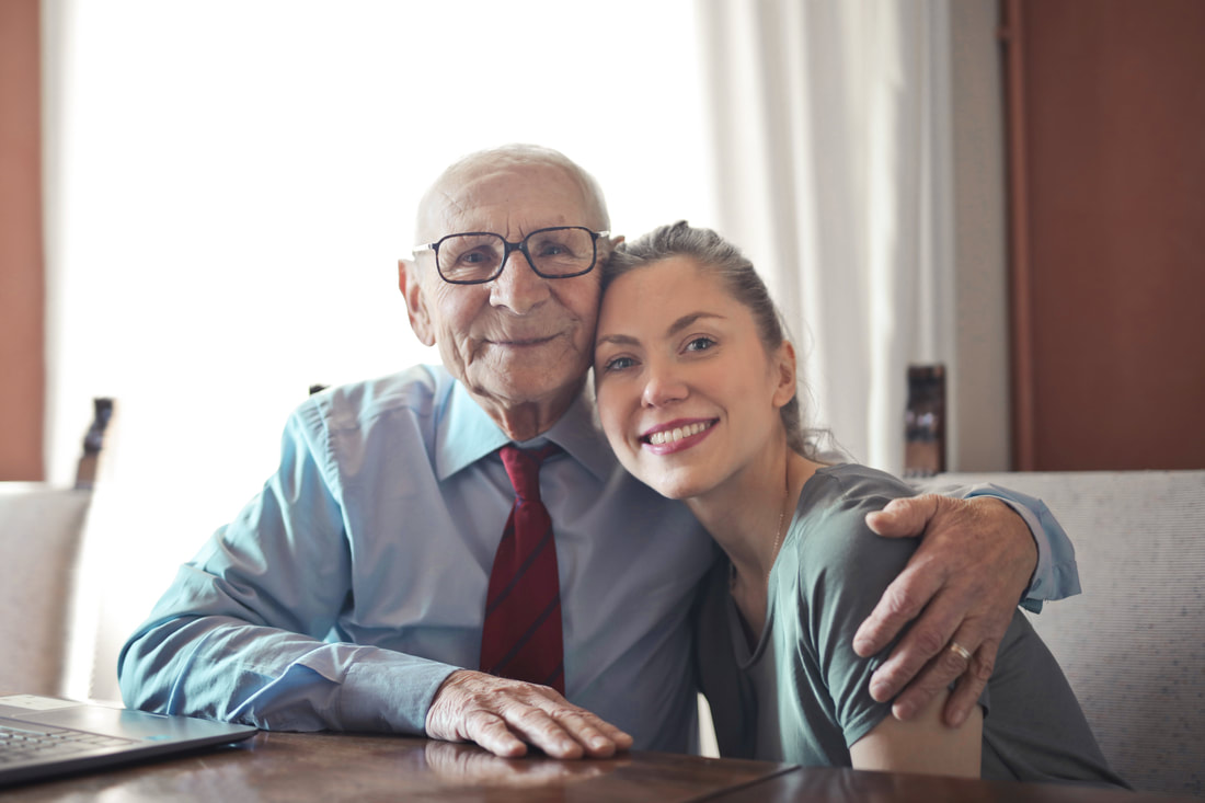 Caregiver smiling with her elderly male patient