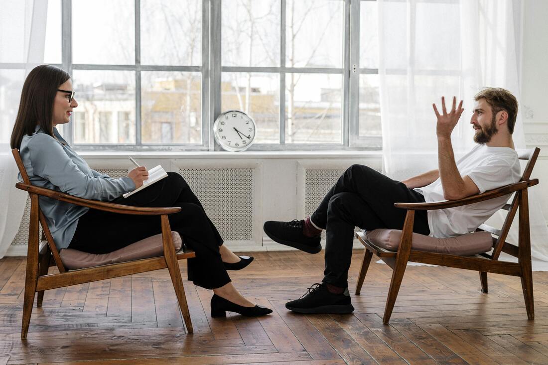 A man talking to a therapist in a well lit room with sunlight