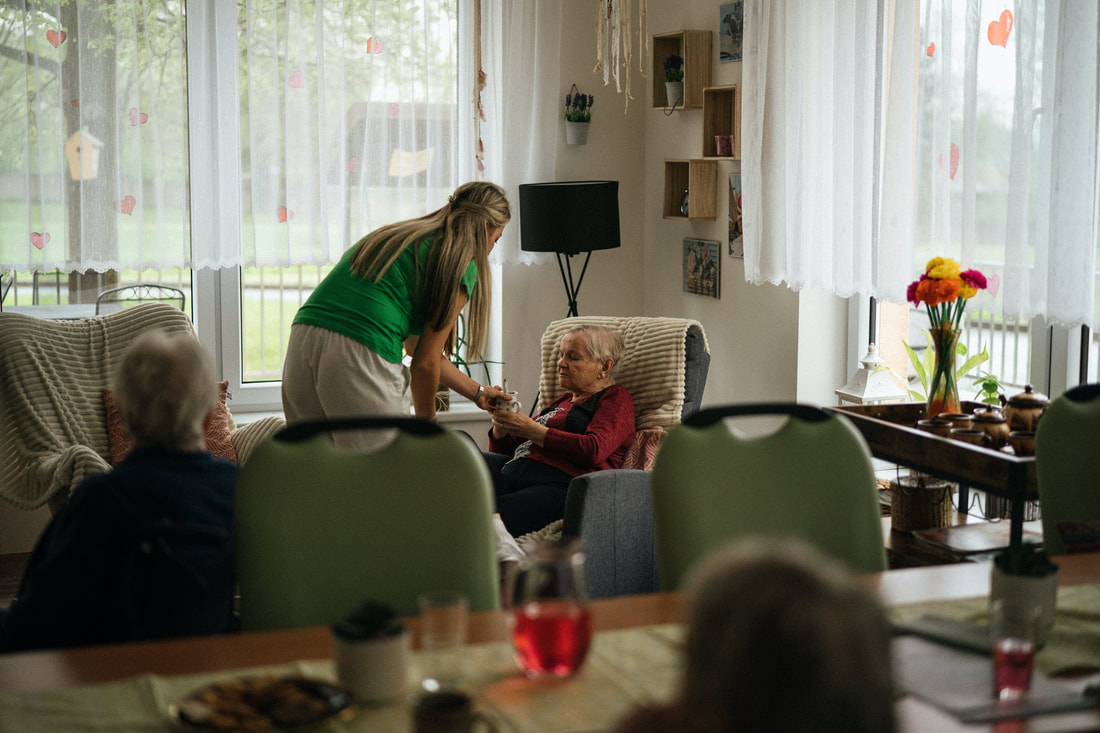 Caregiver attending to two elderly women in a house