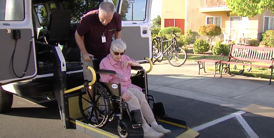 Assisting elderly woman get on a van with wheelchair accessibility functions 
